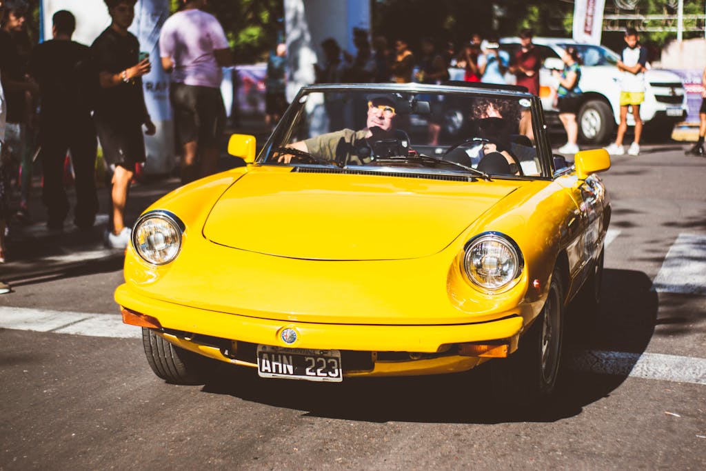 A yellow sports car driving down a street